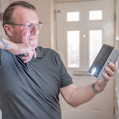 Photo of a client at home looking at his new doorbell and phone alerting equipment